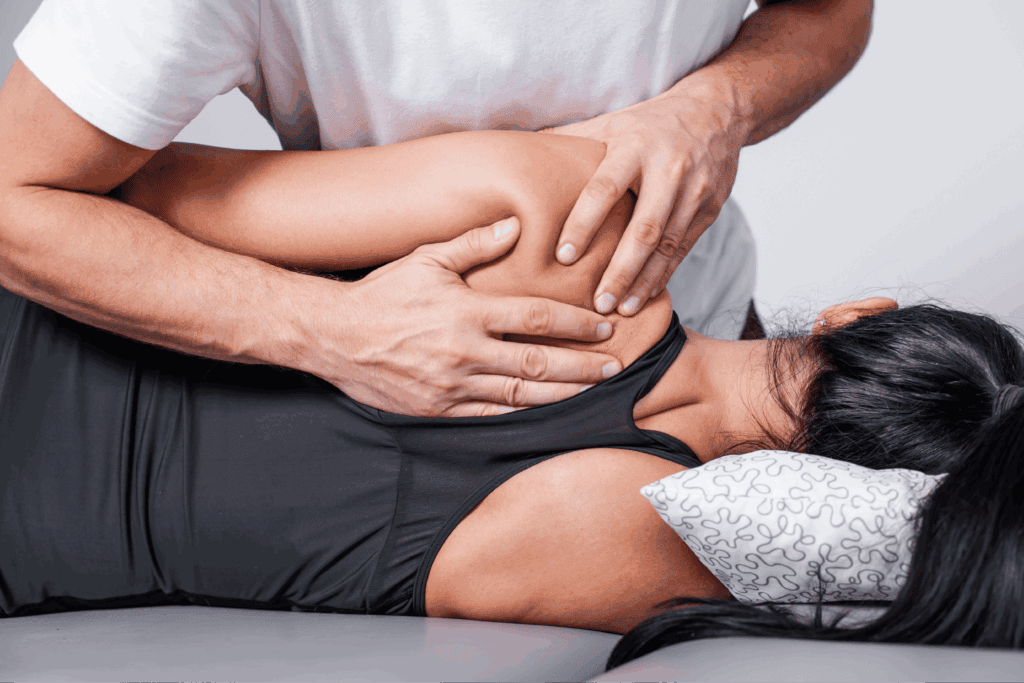 Practitioner providing shoulder and upper-back manual therapy on a treatment table