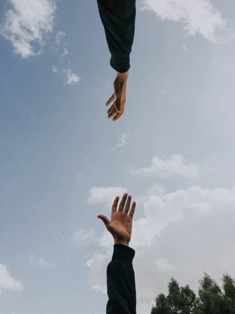 Two people reaching out hands to represent support, care and wellbeing